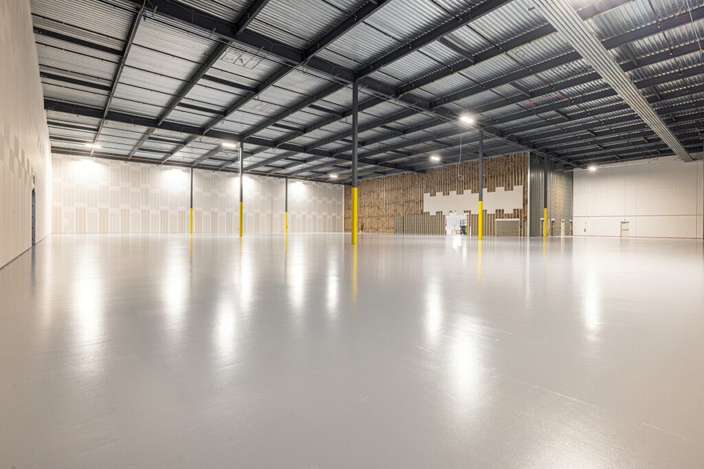 A glossy seamless epoxy floor in a clean industrial warehouse with line markings