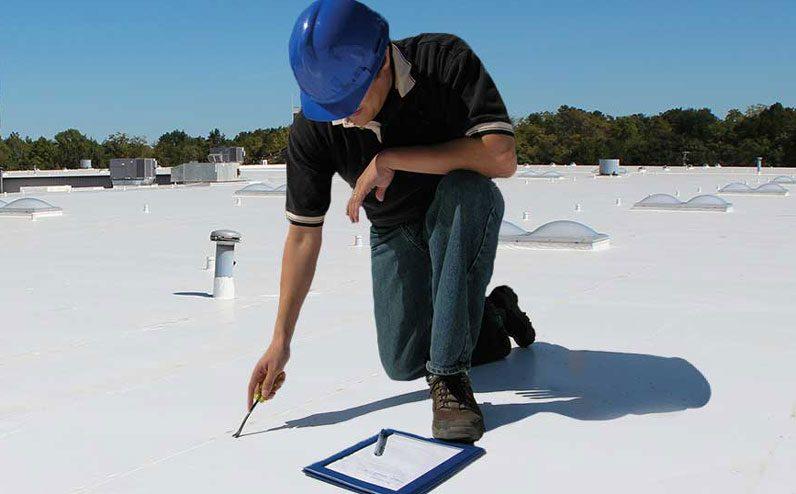 Inspector checking a roof membrane for early signs of cracking or blistering