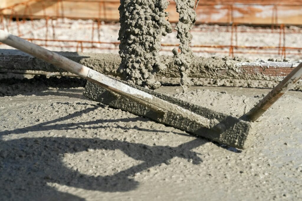 Technician applying corrosion-inhibiting coating to cleaned reinforcement bars before patch repair