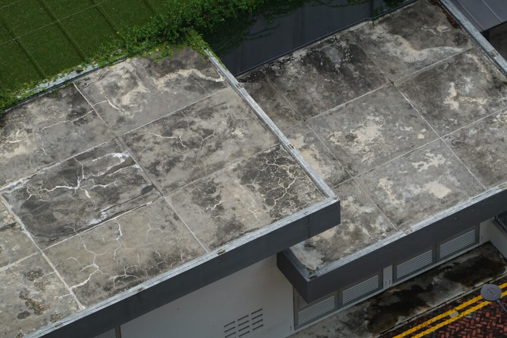 Worker applying liquid waterproofing membrane coating to a concrete roof deck in Qatar