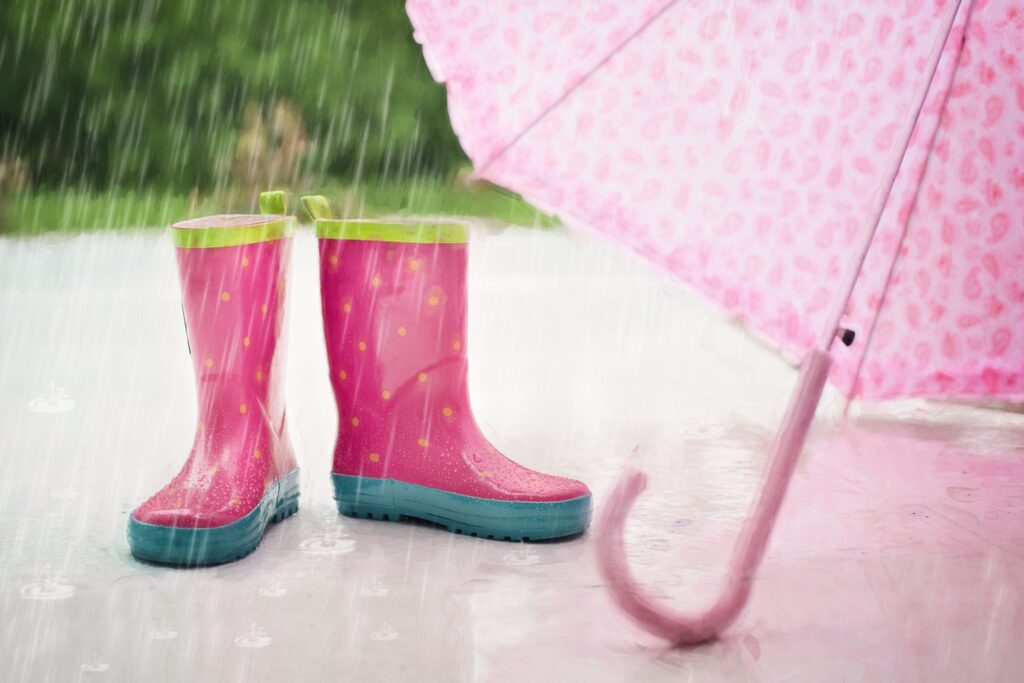 Rain boots and an umbrella catching a sudden downpour, the kind of short intense rain that tests Dubai's roofs and drainage